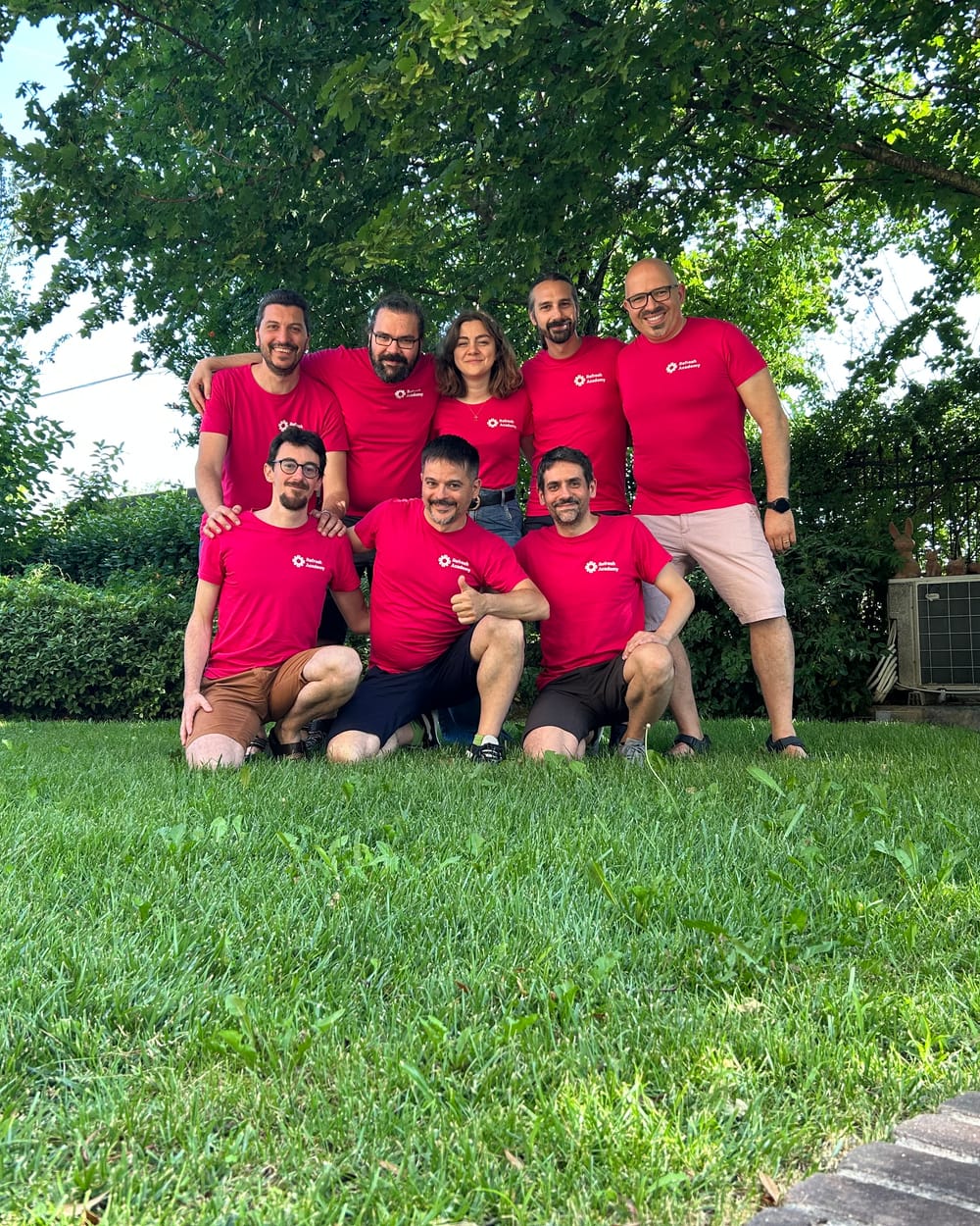 Il team di Refresh Academy in giardino, con le magliette rosse, in posa per una foto di gruppo